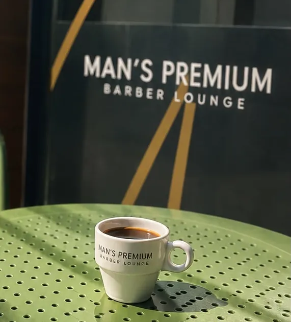 Man's Premium logolu fincanda kahve, dükkân önündeki yeşil masada